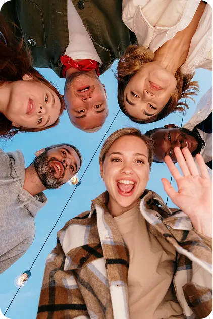 Grupo de jóvenes sonriendo en círculo visto desde abajo